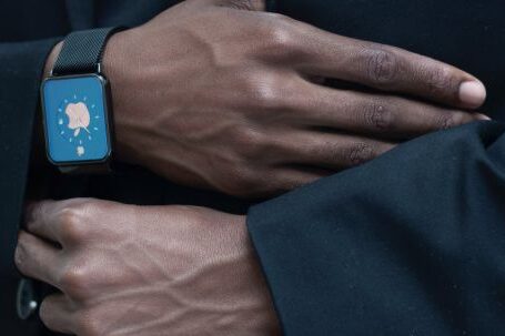 Wearable Fashion - Anonymous person adjusting suit of unrecognizable African American gentleman in elegant outfit with modern smart watch